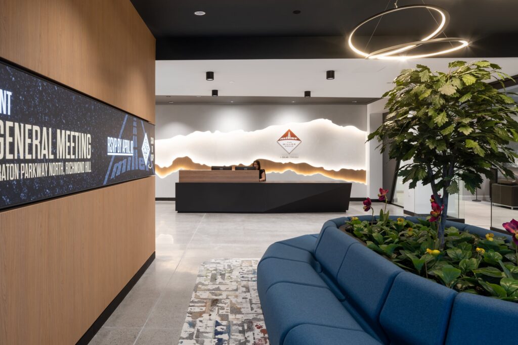 Close-up of a branded reception environment featuring a layered, backlit mountain silhouette wall graphic and corporate logo.