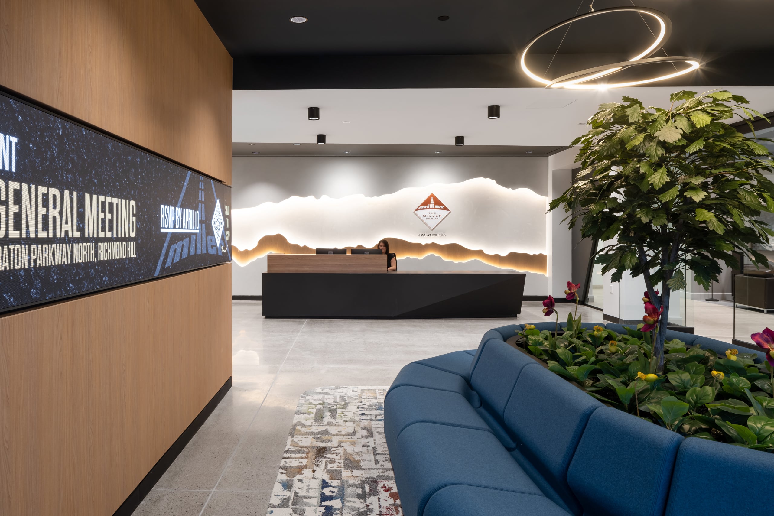 Close-up of a branded reception environment featuring a layered, backlit mountain silhouette wall graphic and corporate logo.