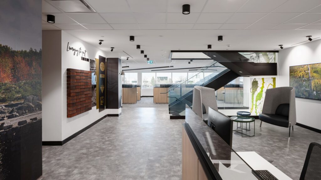A workplace hallway featuring a "Leveraging the Past" storytelling wall with custom brick-textured graphics and dimensional branding elements.