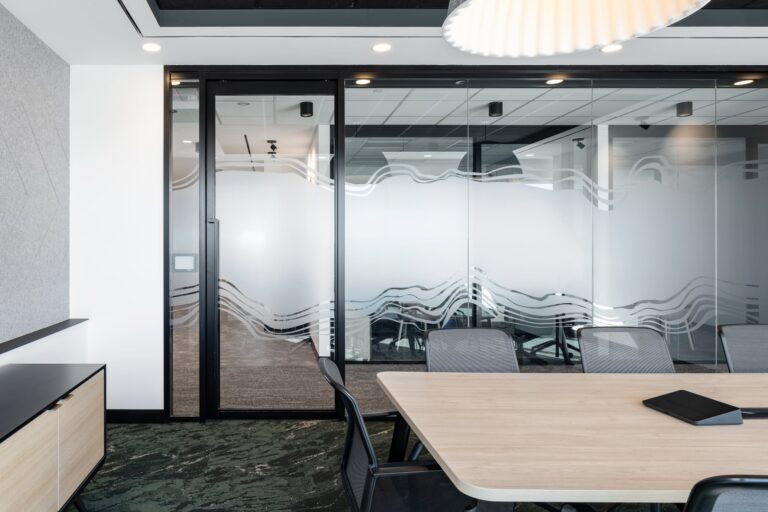 Decorative frosted window film with a custom wave pattern applied to glass office partitions for brand consistency.