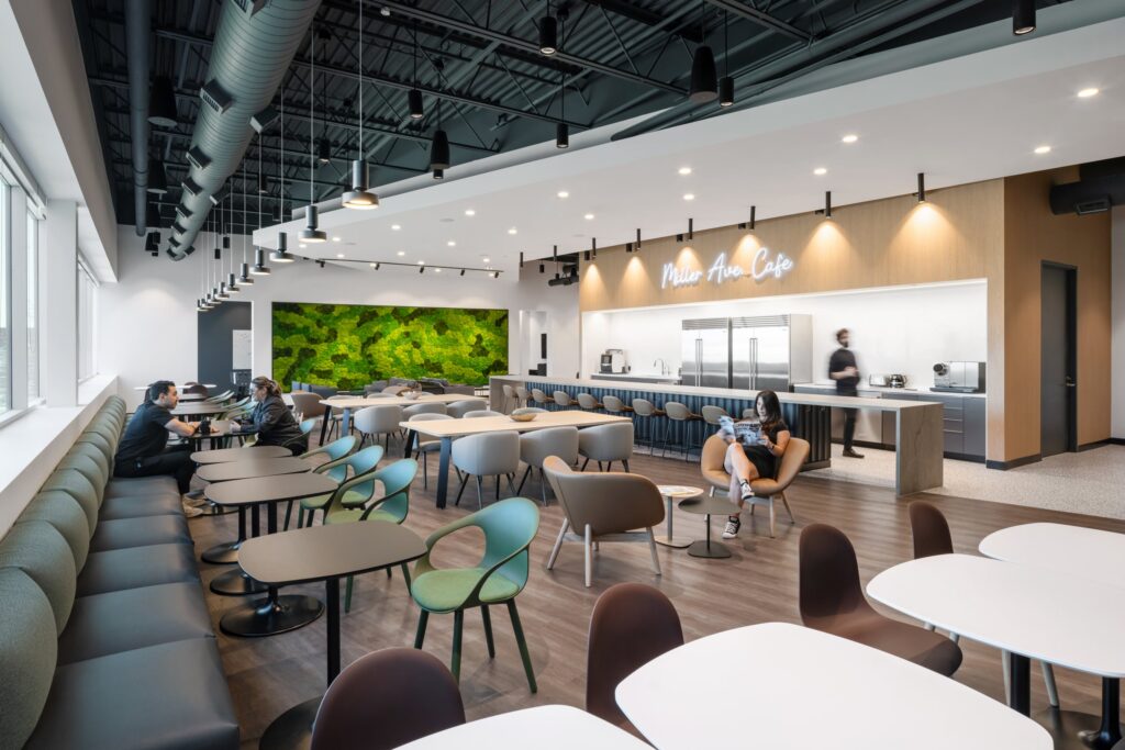 Wide view of a branded corporate lounge featuring custom seating, moss walls, and neon cafe signage.