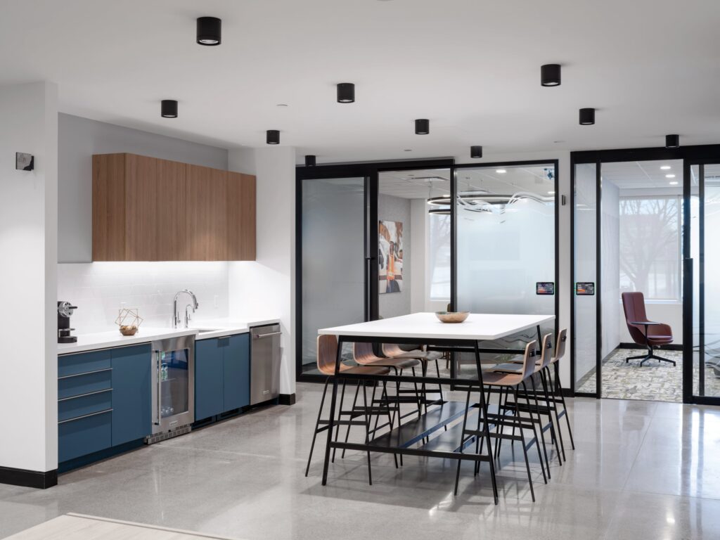 Modern office breakroom and collaboration area featuring frosted glass partitions for privacy and natural light.