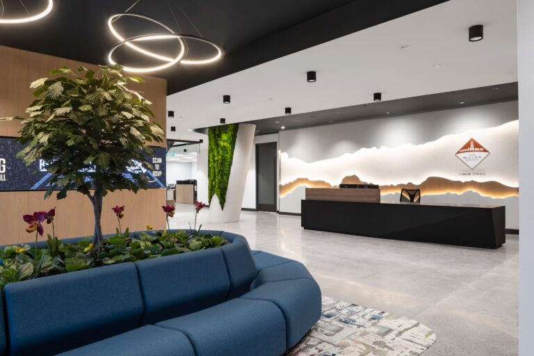 Corporate reception area featuring a backlit architectural wall graphic of a mountain range and a custom logo installation for The Miller Group.
